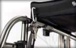 A set of keys hanging from a clip on the frame of a wheelchair.