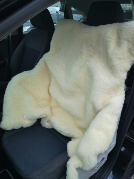 Cream-coloured sheepskin car seat cover draped over a car seat.