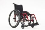 Red lightweight wheelchair with black seat and backrest, featuring large rear wheels and footrests.