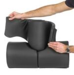 Person holding a black foam roller with a removable cover in a neutral setting.