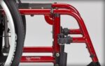 Close-up of a red wheelchair frame showing the structure and components.
