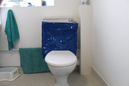 White toilet with a blue protective cover on the cistern in a bathroom setting.