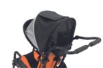 Black and orange stroller with a flip canopy and mesh storage at the back.