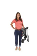 A person holding a folded black chair with wheels, wearing a pink shirt and blue jeans.