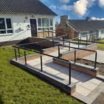 Image: Easirail handrail kits fitted to a dwarf wall in a garden, looking very shiny and new and making life very easy for everyone who uses the Wheelchair ramp