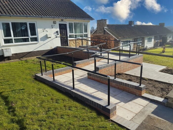 Image: Easirail handrail kits fitted to a dwarf wall in a garden, looking very shiny and new and making life very easy for everyone who uses the Wheelchair ramp