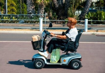 Senior Woman Driving Small Electric Tricycle Vehicle On The Street. Copy Space
