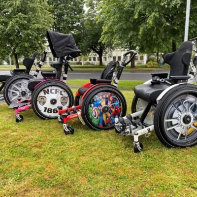 A collection of three custom wheelchairs showcasing unique designs and colors, featuring different wheel styles and seating arrangements.