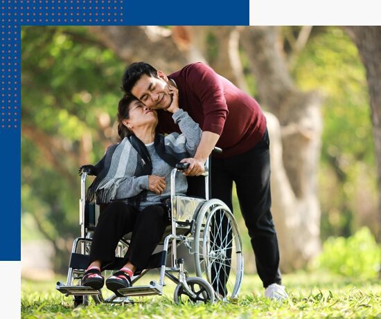 Home 24 Younique Healthcare & Mobility | Wheely Good Wheelchairs in the West Midlands | 0121 630 3850 A man playfully interacting with a woman in a wheelchair in an outdoor setting.