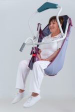 A patient lifting sling with a support frame being used by a seated individual in a clinical setting.