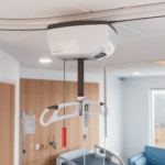 M-Series clinical ceiling lift system installed in a hospital room with a control handle.