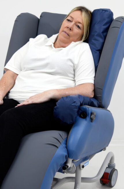 A woman seated in a blue and grey comfort chair with an adjustable backrest.