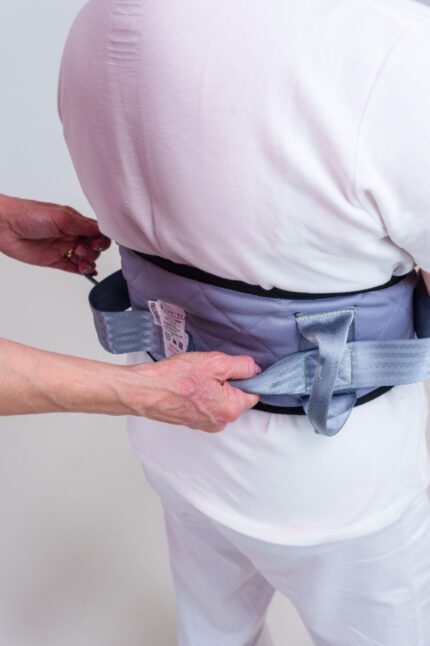 Individual wearing a deluxe safety belt being adjusted by another person from behind.