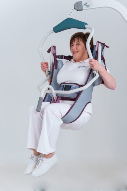 A woman being lifted in a patient sling with support straps, demonstrating the lifting mechanism.