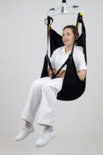A person seated in an in-situ recline sling, suspended from a lifting device.