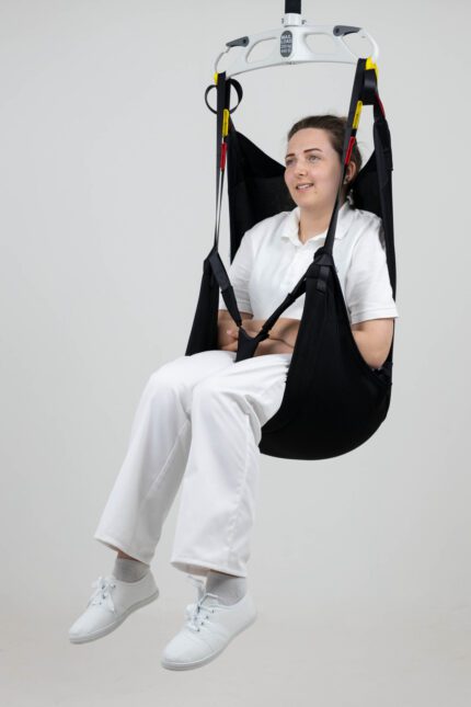 A person seated in an in-situ recline sling, suspended from a lifting device.
