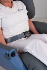 Lap belt secured around the waist of a seated individual in a chair.