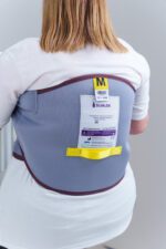 Back view of a person wearing a Silvalea rigid standaid sling with a size label visible.