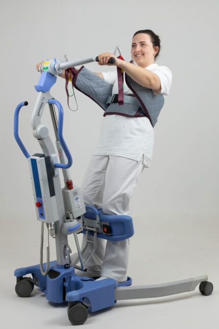 A woman using a stand-up sling lifting device for mobility assistance.