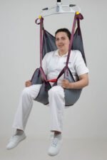 A person seated in a universal deluxe sling designed for patient lifting and support.