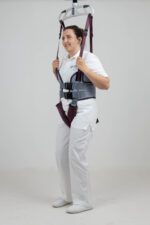 A person wearing a walking harness with support straps for mobility assistance.