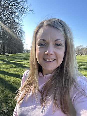 Useful tools 15 Younique Healthcare | Wheelchairs, Powerchairs, Ramps, Healthcare, Rehab, Mobility, Scooters in the West Midlands | 0121 630 3850 A woman with long hair smiling at the camera while standing in a park on a sunny day.
